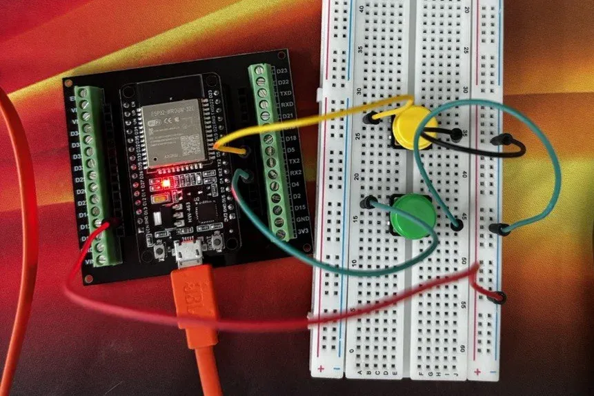 ESP32 breadboard rig emulating the KetoBM meter over BLE, with separate buttons wired up for triggering ketone and glucose readings